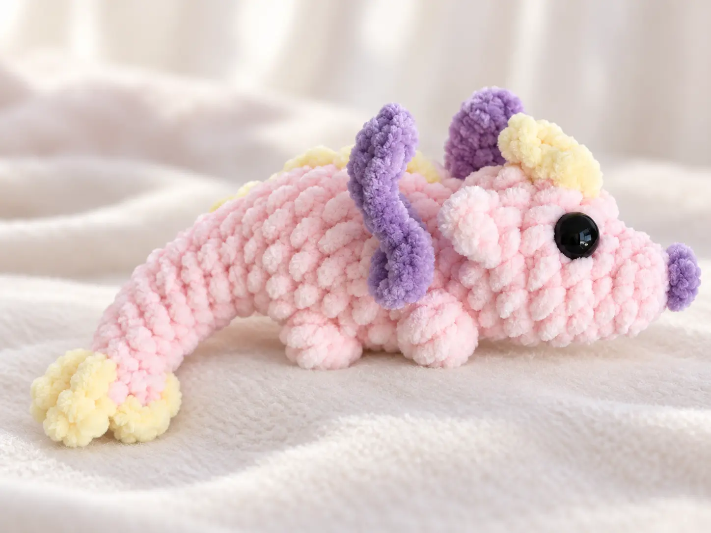 Pastel pink no-sew crochet dragon with purple wings and yellow spikes